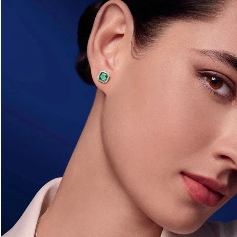 Square Emerald Halo Stud Earrings worn on the ear in a close-up