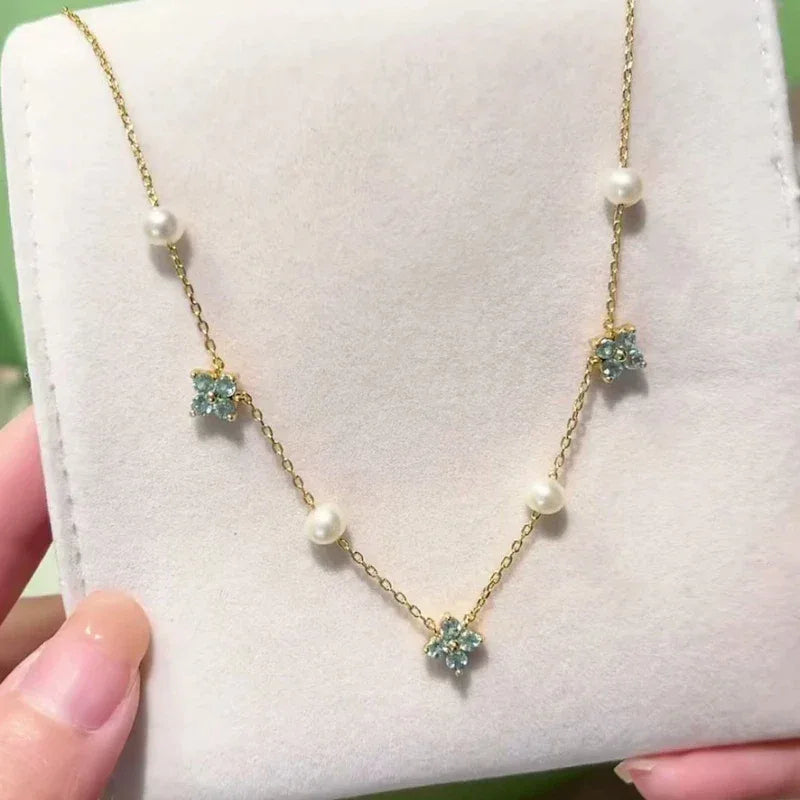Blue Topaz and Pearl Floral Station Necklace — necklace held against a pale display surface