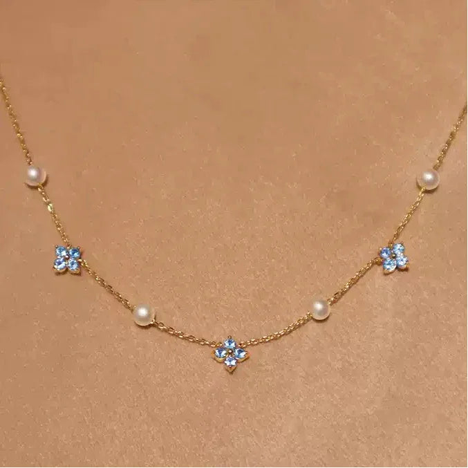 Blue Topaz and Pearl Floral Station Necklace — neckline close-up showing the blue topaz and pearl spacing