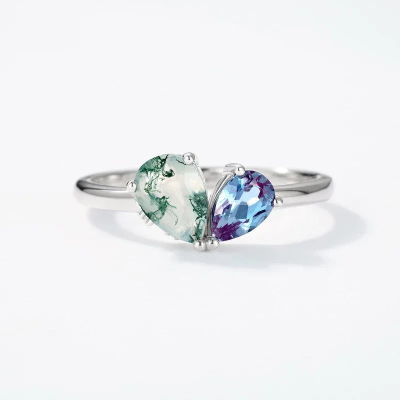 Two-stone Alexandrite open ring in pale green and blue-purple tones, center-stone close-up on a white background