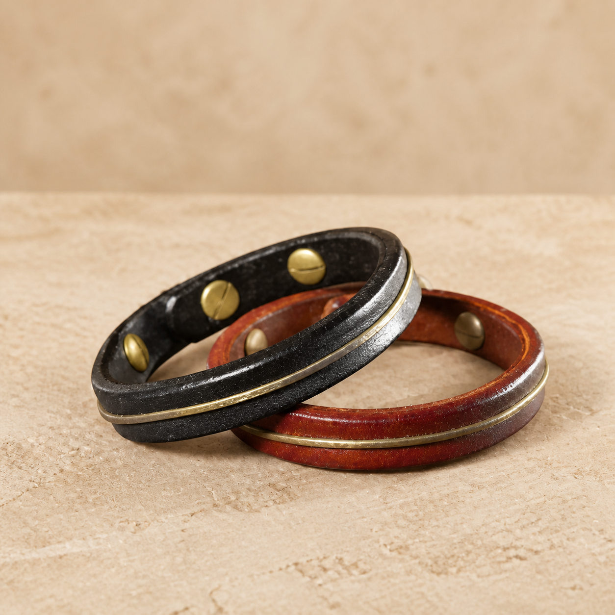Black and brown hand-stitched leather bracelets on a warm neutral background