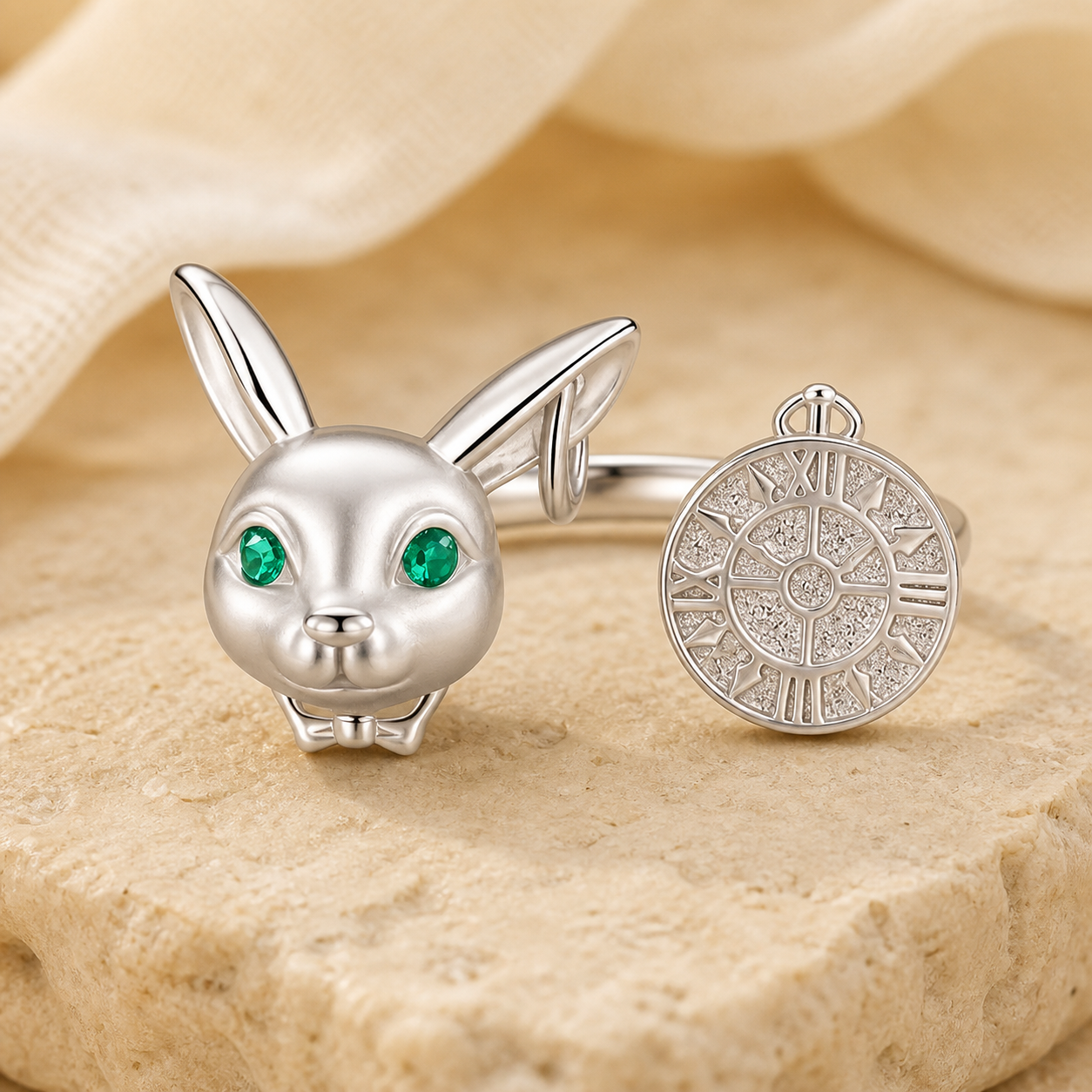Silver white rabbit clock ring with green eyes displayed on warm beige stone beside ivory linen