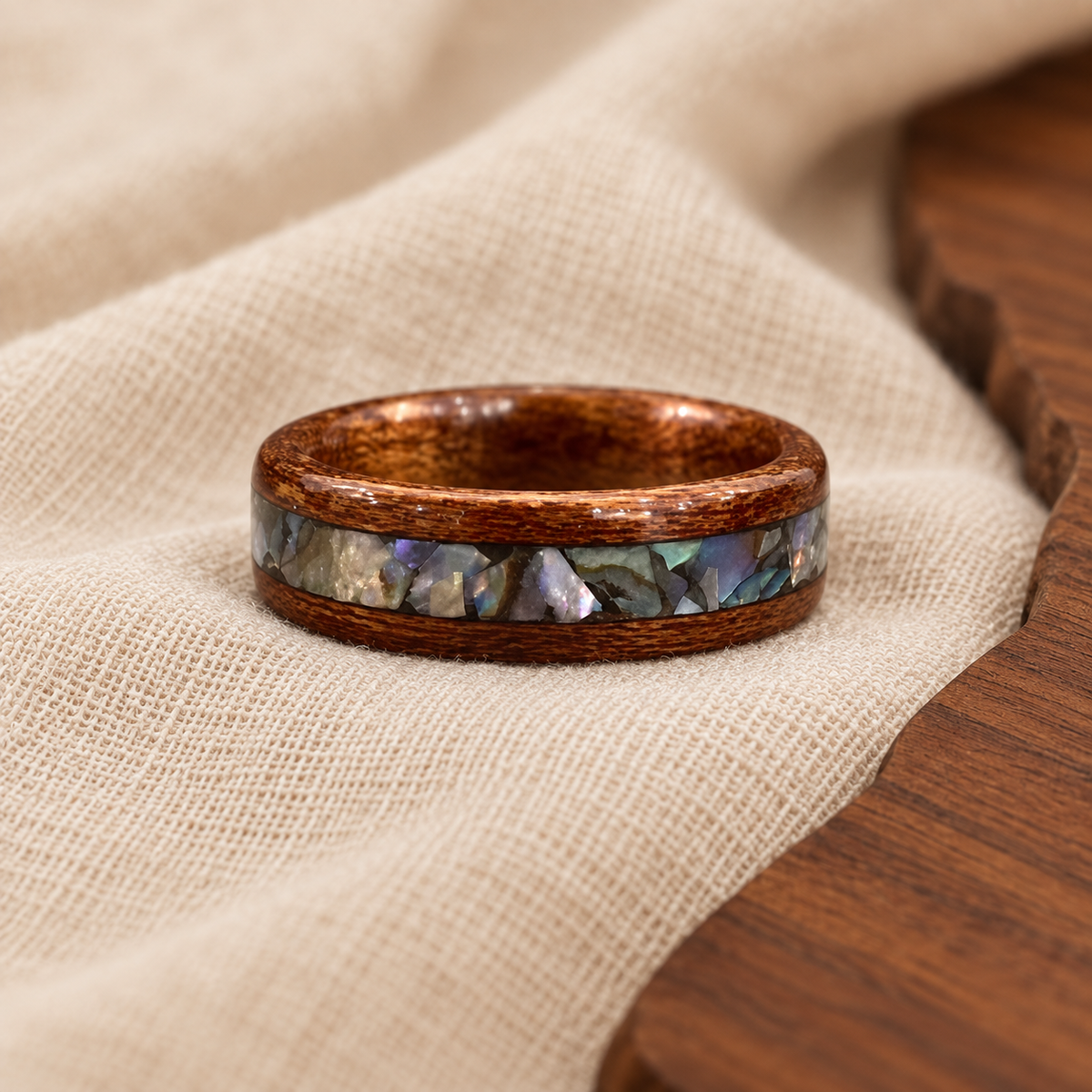 Handcrafted wood ring with iridescent shell inlay on warm ivory linen